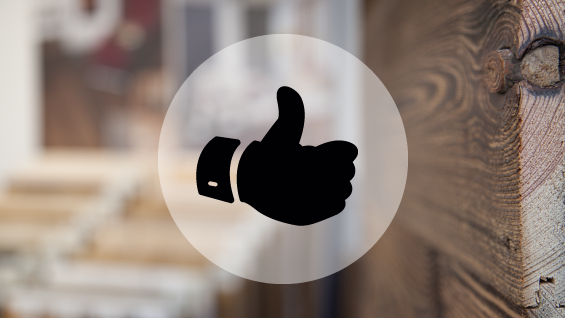 Un pouce levé noir sur fond flou, symbolisant l'approbation ou le soutien dans un environnement intérieur.