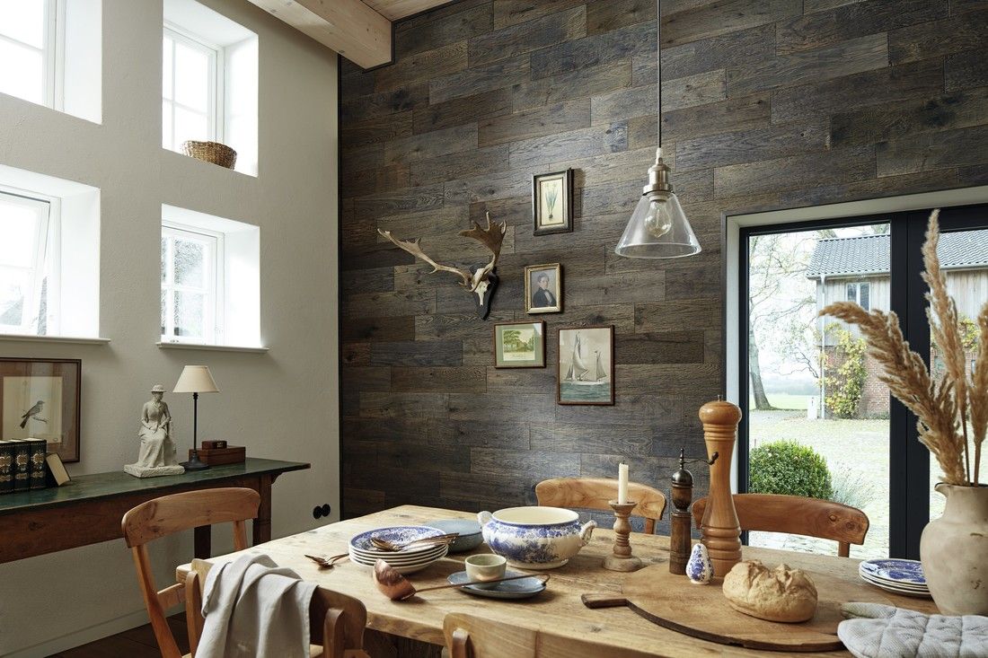 Table en bois avec vaisselle, décorée dans une salle lumineuse aux murs en bois.
