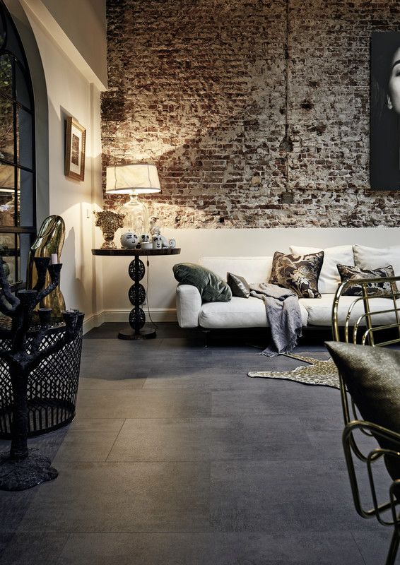 Canapé blanc avec coussins, éclairé par une lampe, dans un salon au mur en briques.