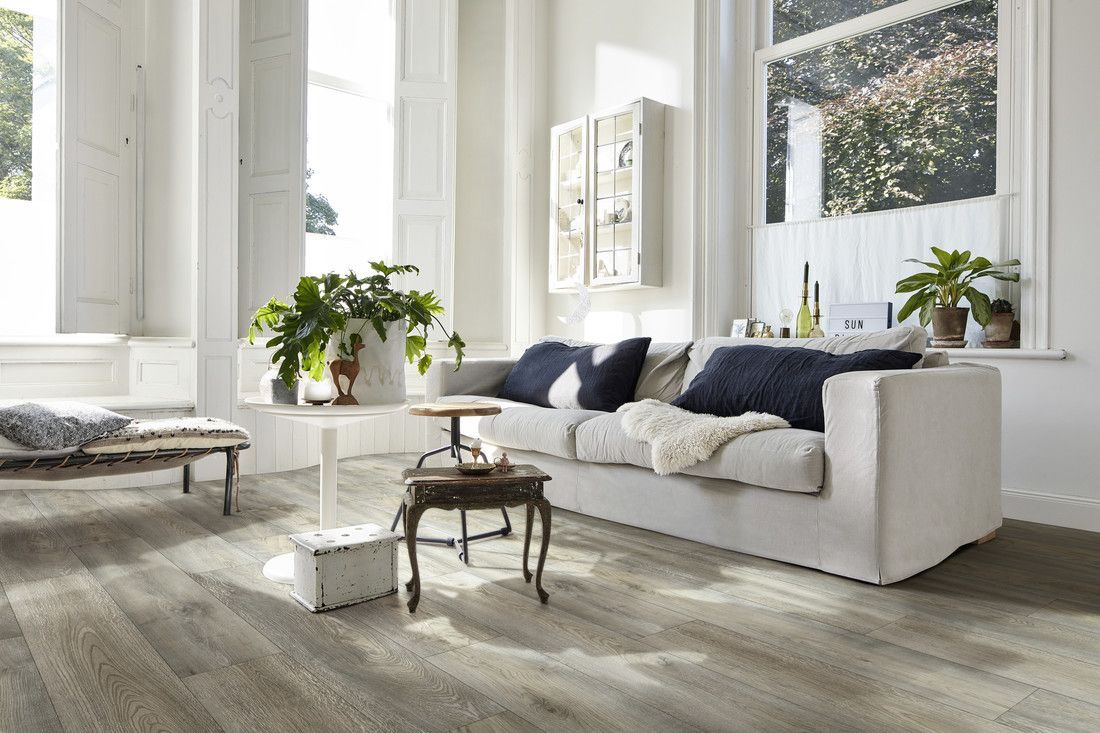 Canapé clair avec coussins, table basse et plantes, dans un salon lumineux et moderne.