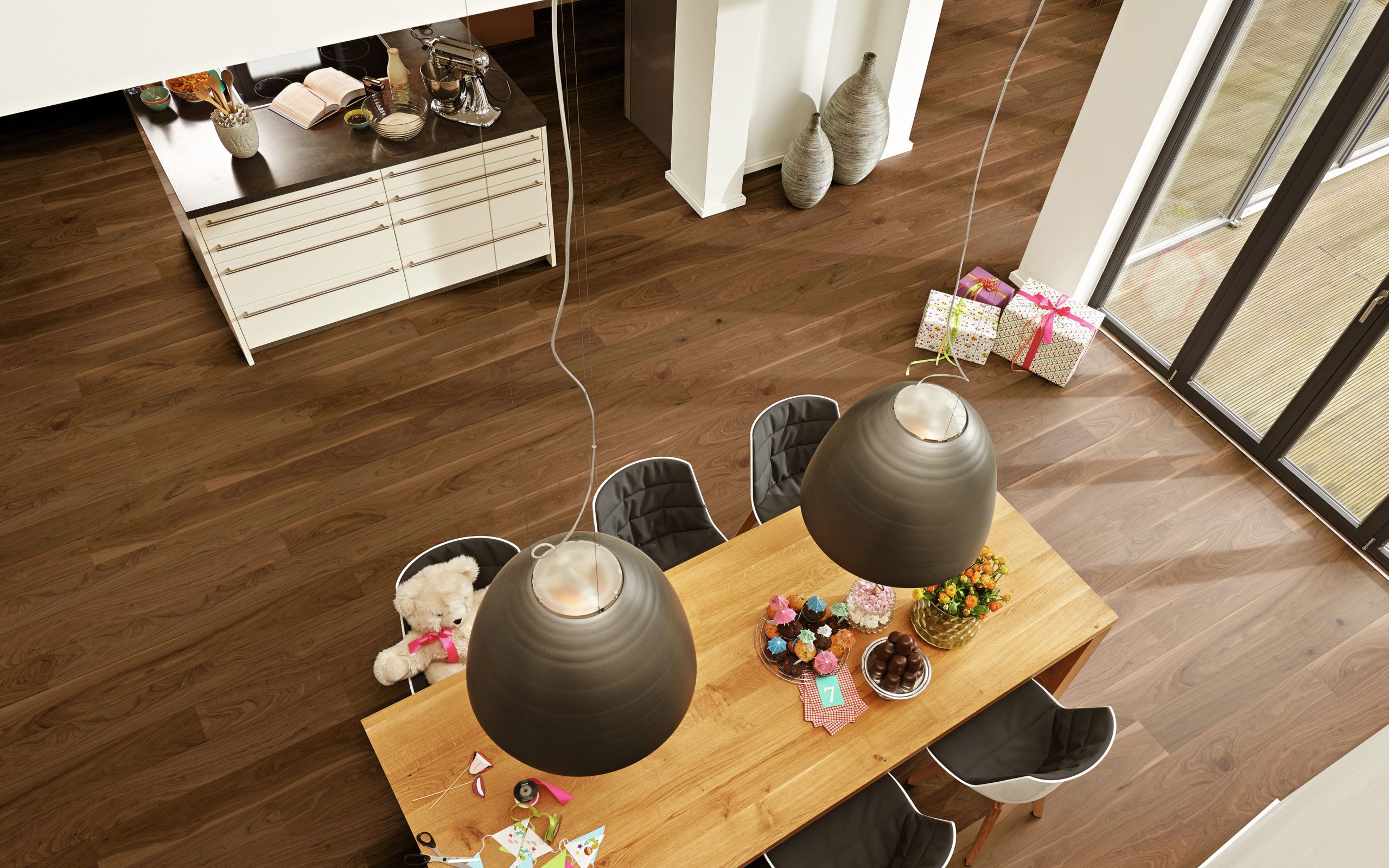 Table en bois avec des décorations, des douceurs et des cadeaux, sous des lampes suspendues.