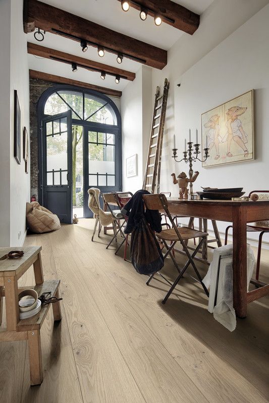 Espace intérieur lumineux avec une table, des chaises, des œuvres d'art et une porte vitrée.