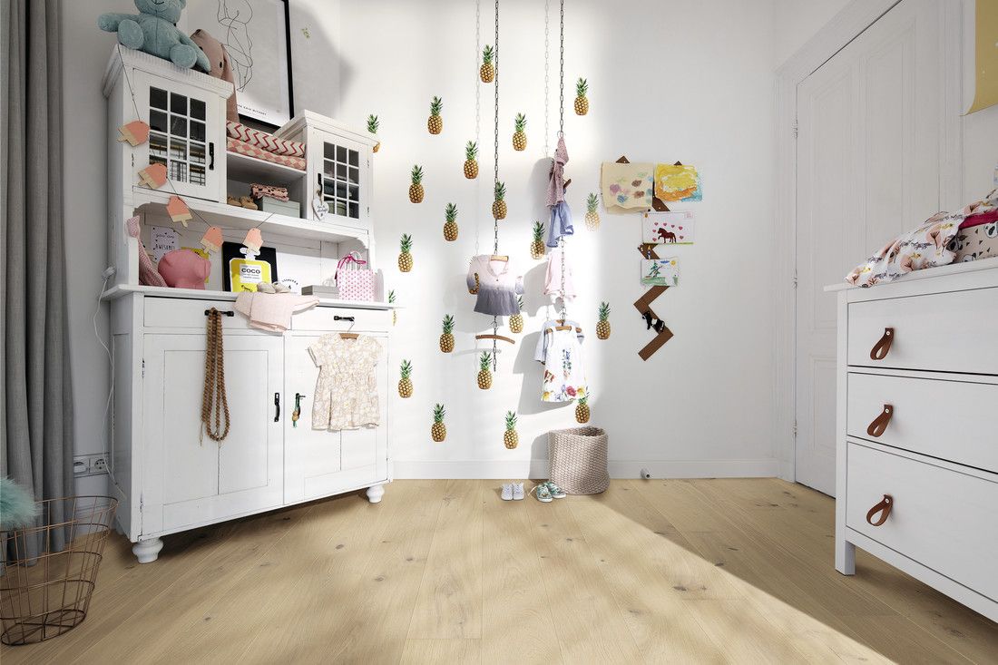 Chambre lumineuse avec meubles blancs, vêtements suspendus, décorations ananas et jouets en peluche.