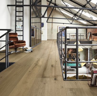 Espace intérieur moderne avec un sol en bois, un fauteuil et une mezzanine visible.