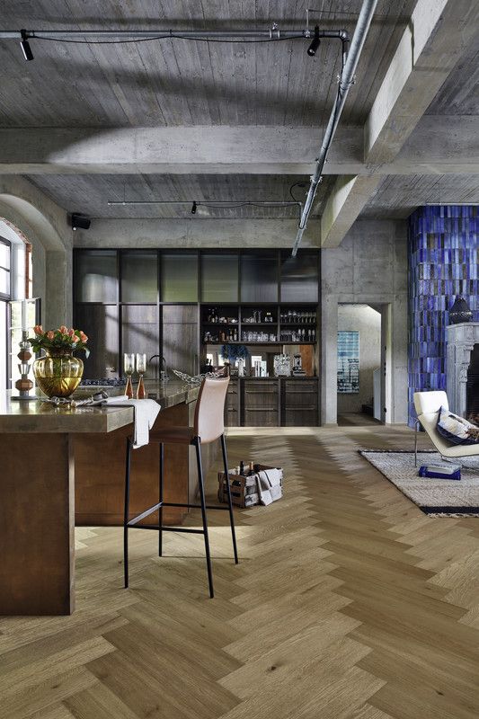 Espace intérieur moderne avec un bar, des chaises, et un sol en bois en chevron.