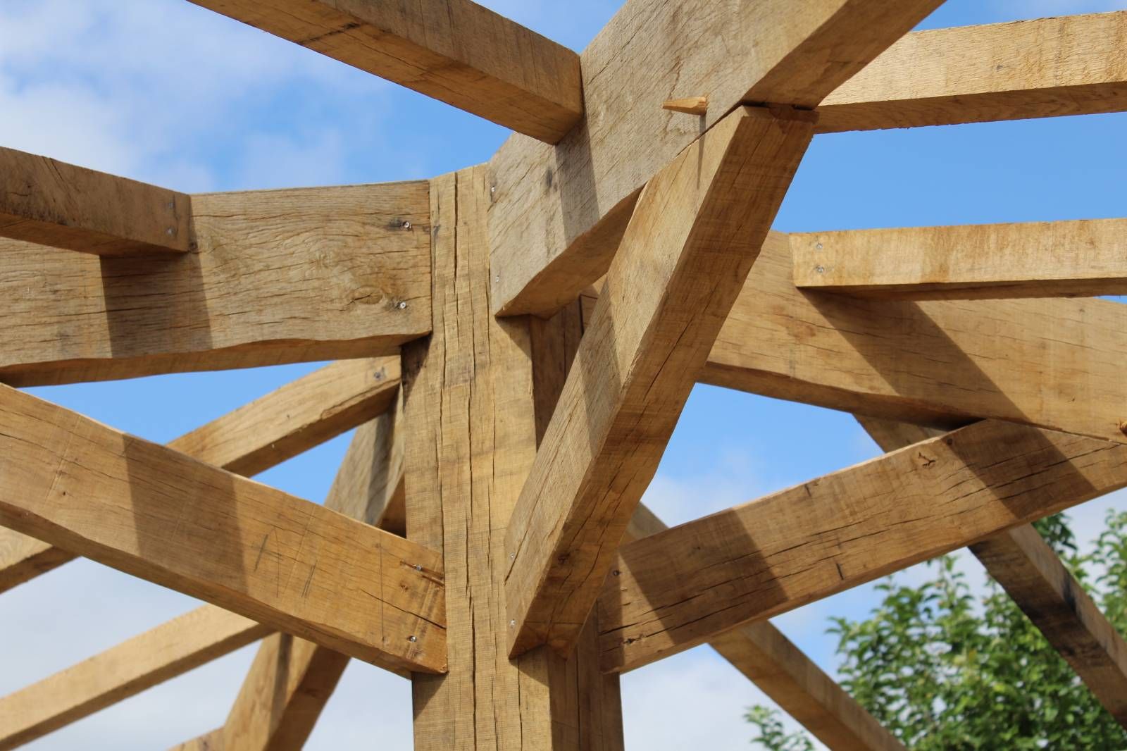 Structure en bois, soutenue par des poutres, sous un ciel bleu avec quelques nuages.
