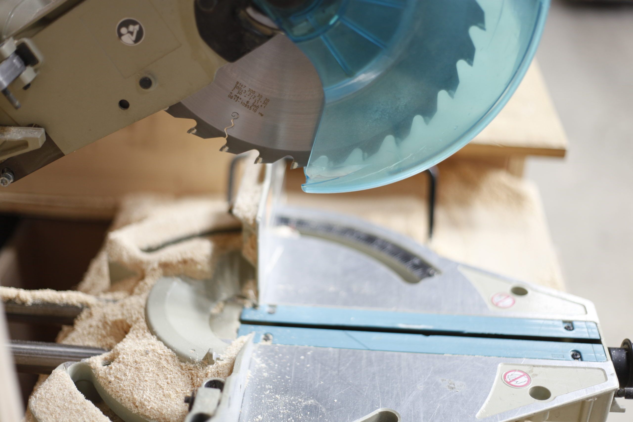 Scie circulaire en action, coupant du bois, avec des copeaux de bois éparpillés autour.