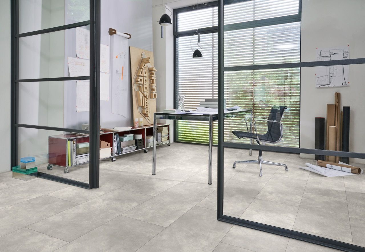 Bureau moderne avec une table, des chaises, des étagères et des fenêtres laissant entrer la lumière.