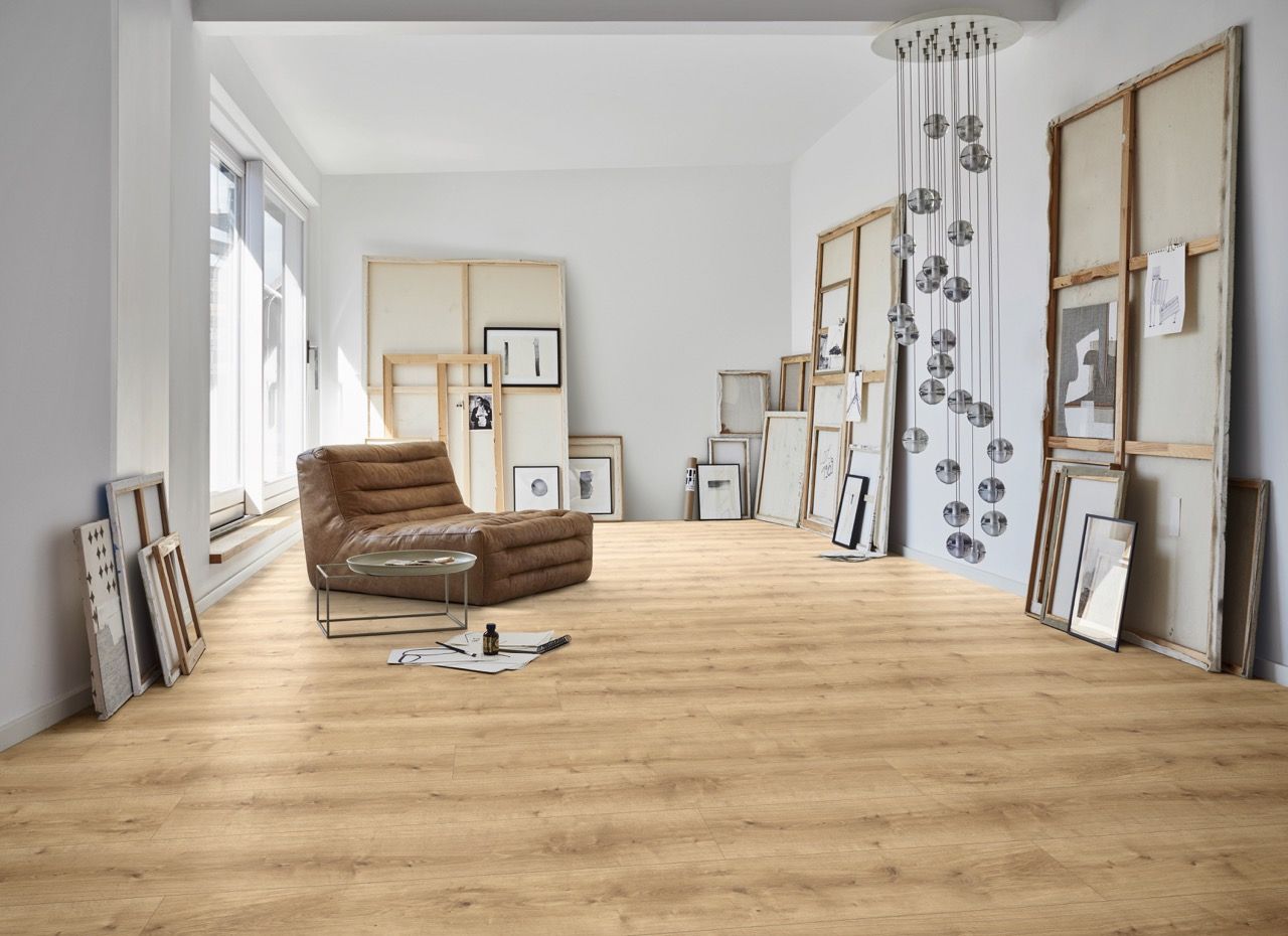 Un canapé marron est placé dans une pièce lumineuse avec des cadres accrochés aux murs.