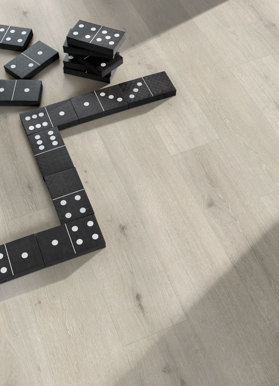 Des dominos noirs sont disposés sur un sol clair, certains empilés, d'autres alignés.