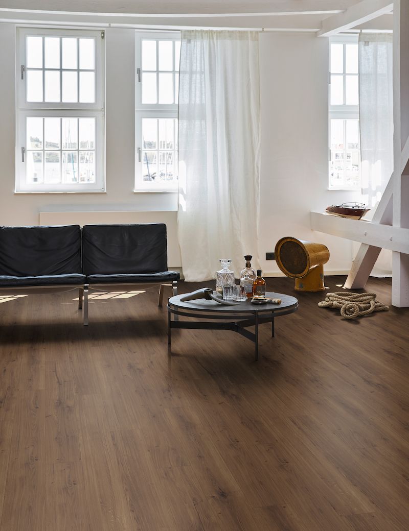 Un canapé noir est placé devant une table basse, dans un intérieur lumineux et moderne.