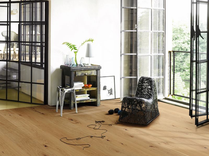 Chaise en fil métallique, posée sur un sol en bois, dans un intérieur lumineux et aéré.