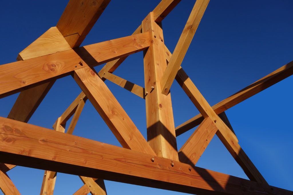 Structure en bois, soutenue par des poutres, se dresse contre un ciel bleu dégagé.