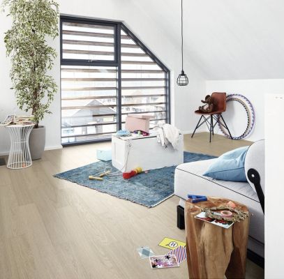 Salon moderne avec un tapis, un canapé, des jouets éparpillés et une grande fenêtre lumineuse.