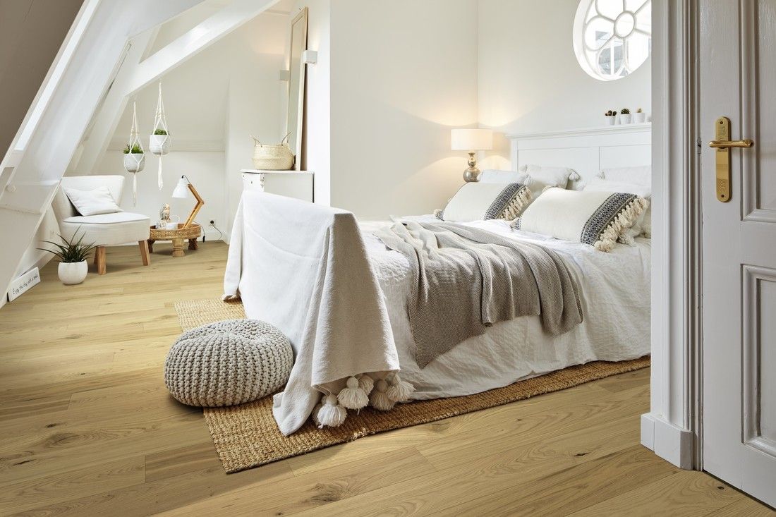 Chambre lumineuse avec lit, fauteuil, plantes et décor minimaliste, créant une ambiance apaisante.