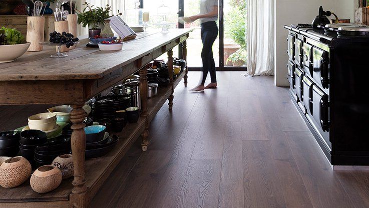 Cuisine moderne avec un plan de travail en bois, une personne se déplaçant près de la fenêtre.