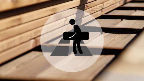 Un ouvrier transporte une planche de bois sur un sol en bois, en pleine construction.