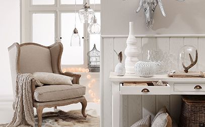 Canapé gris avec coussins décoratifs, une table en bois, éclairage doux, ambiance chaleureuse.