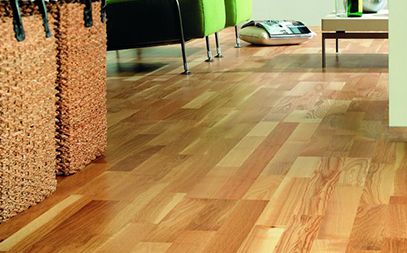 Salon lumineux avec un canapé confortable, une table en bois et un sol en parquet clair.