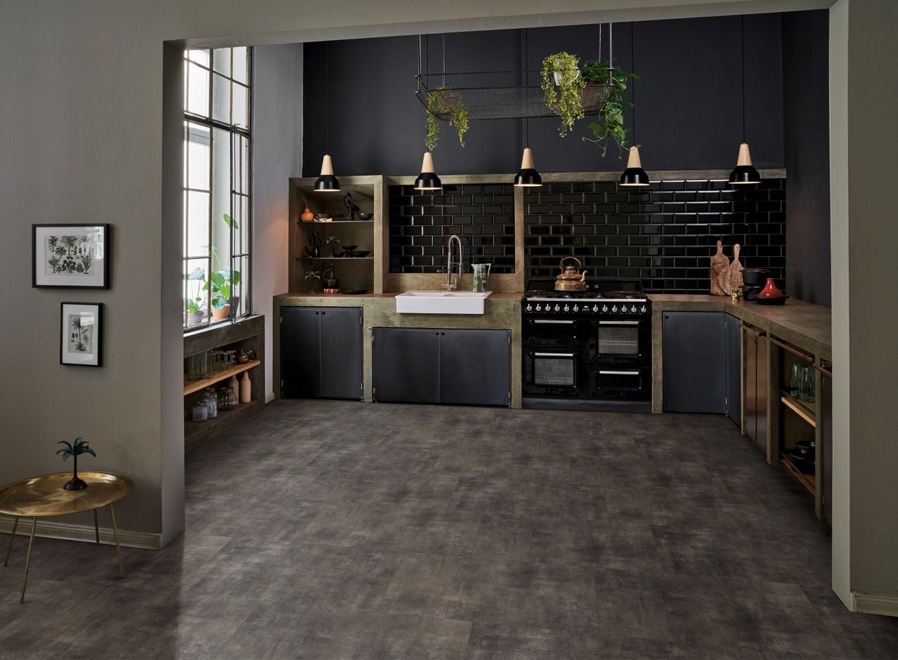 Cuisine moderne avec un évier, un four noir et des étagères, décorée de plantes suspendues.