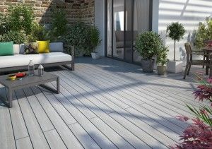 Terrasse moderne avec canapé, table basse, plantes, et chaises, offrant un espace de détente.