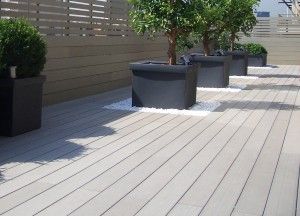 Terrasse en bois avec des pots de plantes vertes disposés symétriquement, créant une ambiance apaisante.