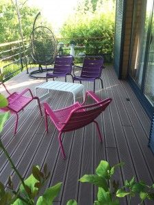 Chaises colorées disposées sur une terrasse, entourées de verdure, créant un espace convivial.