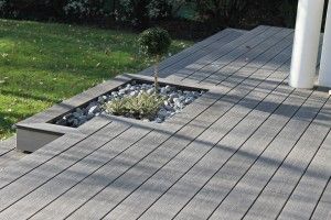 Terrasse en bois avec un petit arbre et des pierres décoratives dans un espace aménagé.