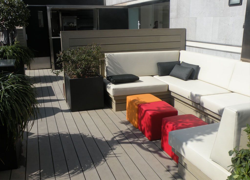 Espace extérieur moderne avec un canapé blanc, des poufs colorés et des plantes décoratives.