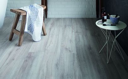 Un tabouret en bois et une petite table blanche sont placés sur un sol clair.